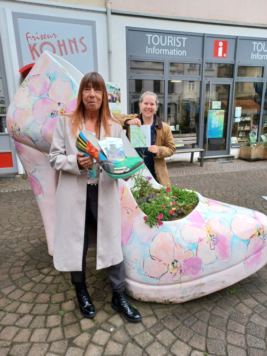 Vor der Tourist-Info in Montabaur präsentieren Karin Maas und Kerstin Kux das neue Booklet „Von Schuh zu Schuh“