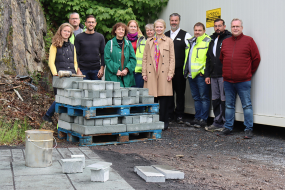 Ein grünlicher Naturstein wird künftig die Gehwege, Plätze und Parkbuchten an der neu gestalteten Bahnhofstraße in Montabaur schmücken. Am Fuße des Schlossbergs trafen sich die Projektbeteiligten, um die Musterfläche mit dem „Monte Verde“ genannten Pflaster zu sehen und zu begehen. Interessierte können die Musterfläche gegenüber der Post hinter dem Bauzaun betrachten. (Bild: VG Montabaur)