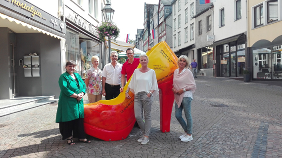 Stoff zum Nachdenken liefert der „Zitate-Schuh“ in der oberen Kirchstraße. Der in warmen Rot- und Gelbtönen gestaltete Mon-Stiletto ist mit Zitaten und Sprüchen zum Thema Füße, Weg und Laufen überzogen. Im Vorbeischlendern kann man so den einen oder anderen Denkanstoß mitnehmen – so die Intention der Sponsoren. Für diesen Mon-Stiletto haben sich die benachbarten Betriebe Modeteam, Casa Nuova, Pfannen Oster, Töpferlädchen und Flach Augenoptik zusammengetan und den Maler Michael Kleck mit der Gestaltung beauftragt.