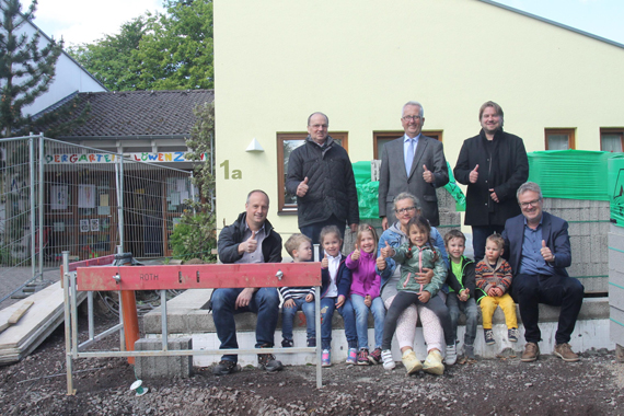 Baubeginn an der Kita Löwenzahn in Elgendorf. Das Fundament für den Anbau ist schon fertig. Darauf haben mit den Kindern Platz genommen (hinten v.l.): Ortsvorsteher Hermann Wolf, der erste Stadtbeigeordnete Gerd Frink und Architekt Björn Merzbach sowie (vorne v.l.) Projektleiter Markus Felsing von der Verbandsgemeinde Montabaur, Kita-Leiterin Judith Böcker und Guido Göbel, Fachbereichsleiter Kindertagesstätten bei der Verbandsgemeinde.