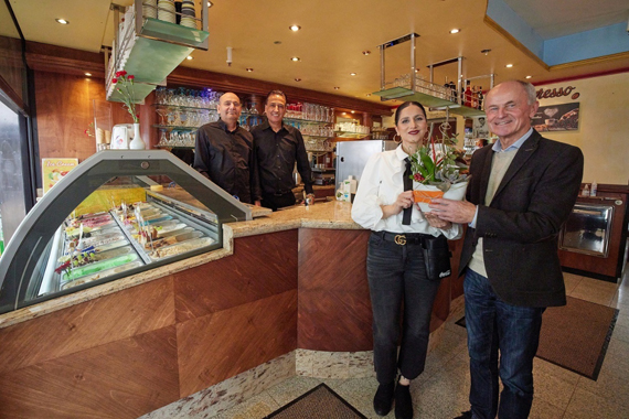Das Bild zeigt vier Personen im Eiscafé bei der Eröffnung.