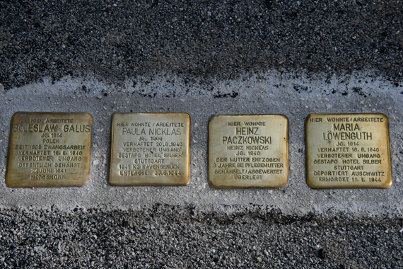 Das Bild zeigt 4 nebeneinander liegende, in den Boden eingelassene, bronzene Erinnerungstafeln mit eingravierten Daten