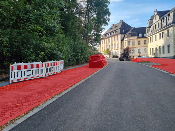 Außenaufnahme eines Straßenabschnitts, bei dem die Gehwege auf beiden Seiten rot markiert sind