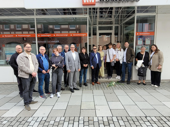 Das Bild zeigt eine Gruppe von Personen, die vor einem Gebäude stehen.