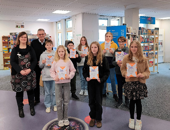 Das Bild zeigt eine Gruppe von Kindern, die Urkunden in den Händen halten, und zwei Erwachsene