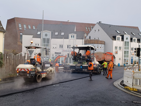 Außenaufnahme eines Straßenabschnittes mit Straßenarbeitern beim Asphaltieren