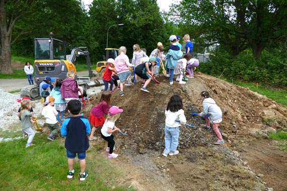 Das Bild zeigt eine Gruppe von Kindern auf dem Erdhügel einer Baustelle