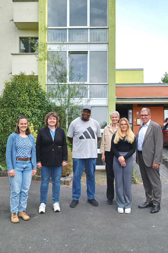 Das Bild zeigt sechs erwachsene Personen vor einem Gebäude 