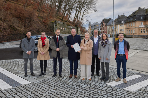 Außenaufnahme einer Gruppe von acht erwachsenen Personen in einem neu gestalteten Straßenbereich