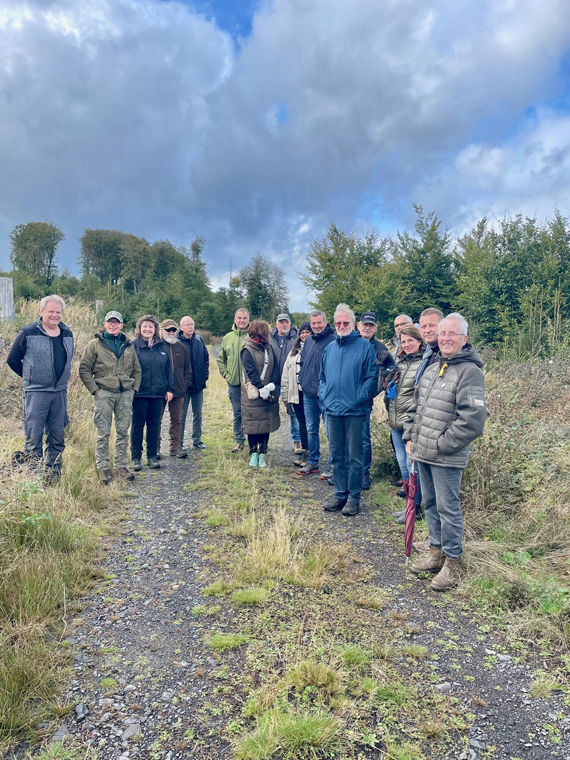 Das Bild zeigt eine Gruppe von Erwachsenen auf einem Waldweg